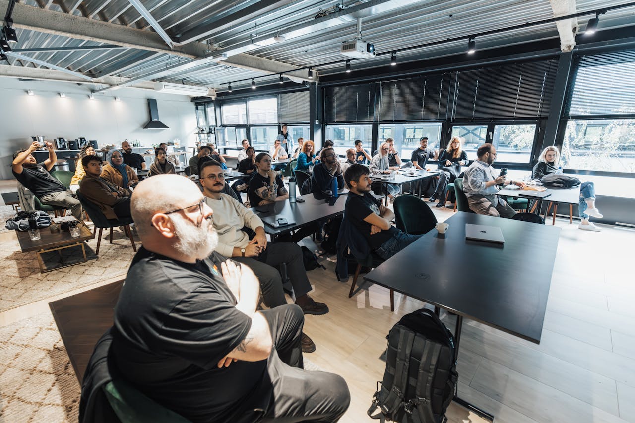 gallery-01 A diverse group of professionals attentively listening during an indoor business meeting in a modern conference room.