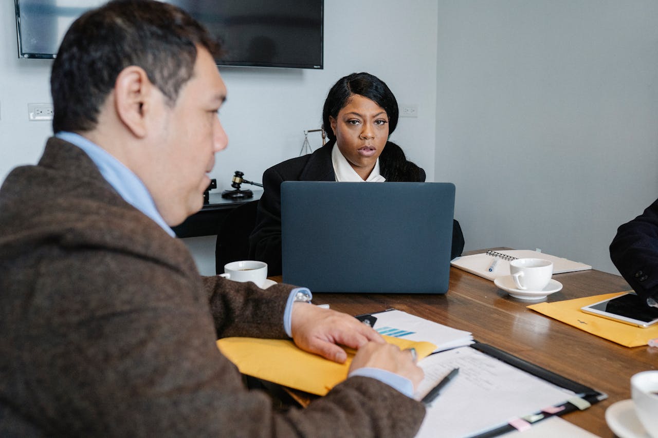 gallery-03 Group of multiethnic coworkers in formal wear sitting at table with laptop and documents while discussing business issues